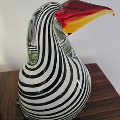 a colorful bird shaped vase sitting on top of a wooden table