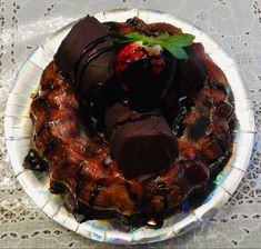 a plate topped with chocolate covered desserts on top of a white doily table