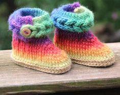 a pair of colorful knitted baby booties sitting on top of a wooden bench