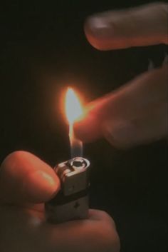 someone lighting a lighter in the dark with one hand and another holding an electronic device