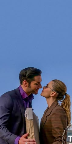 a man and woman standing next to each other in front of an airplane flying overhead