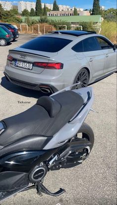 two motorcycles parked next to each other in a parking lot with cars and buildings behind them