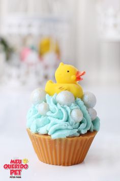 a cupcake with blue frosting and a rubber ducky on top is shown