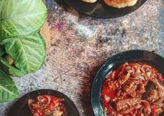 three black plates filled with food on top of a table next to green leafy plants