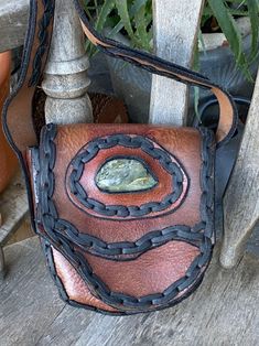 a brown and black purse sitting on top of a wooden bench