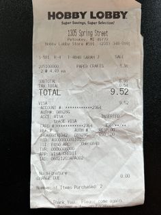 a receipt from hobby lobby sitting on top of a black table next to a cell phone