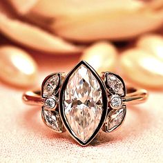 an engagement ring with a pear shaped diamond in the center and two smaller pear shaped diamonds on each side