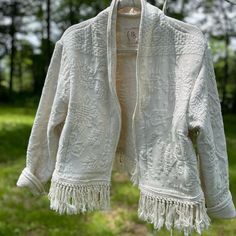 a white jacket hanging on a clothes line in front of some green grass and trees