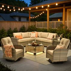 an outdoor living area with wicker furniture and string lights strung over the top of it