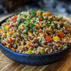 a bowl filled with rice and vegetables on top of a wooden table