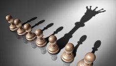 the shadow of a person standing in front of chess pieces on a dark background with light coming