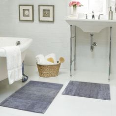 a white bathroom with blue rugs on the floor