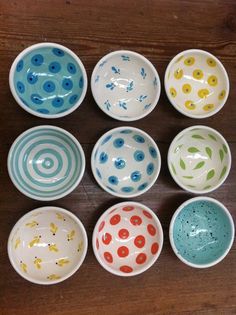 six bowls with different designs on them sitting on a wooden table next to each other