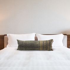 a white bed with two lamps on either side and a pillow on the other side