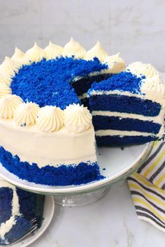 a blue velvet cake with white frosting on a plate next to a slice cut out