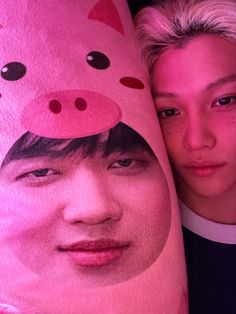 a man and woman are posing for a photo with a pink pig blanket on their head