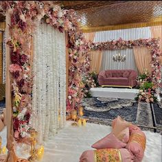 a living room decorated in pink and gold with flowers on the wall, couches, candles and rugs