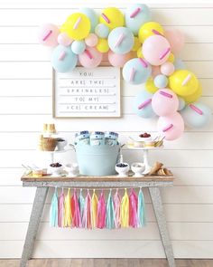 a birthday party with balloons, cake and desserts on a table in front of the wall