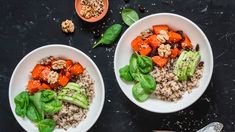 two white bowls filled with food on top of a black table next to an orange and green pepper