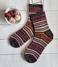 a pair of socks sitting next to a bowl of balls of yarn