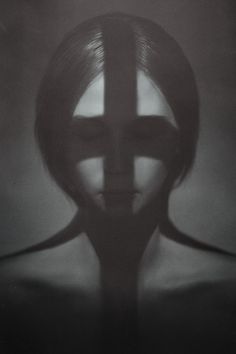 a black and white photo of a woman's face with the cross behind her head