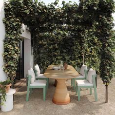 an outdoor dining area with table, chairs and potted plants on the side wall