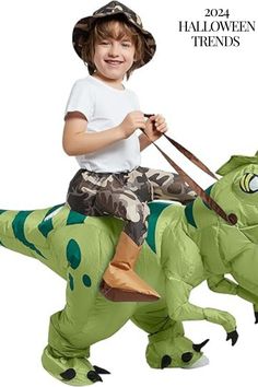 a young boy riding on the back of a green dinosaur inflatable halloween costume