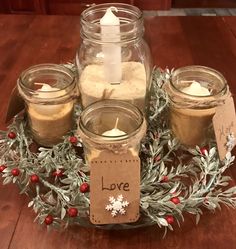 three jars filled with candles sitting on top of a wooden table