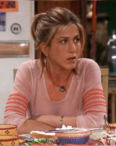 a woman sitting at a table in front of plates and cups with food on it