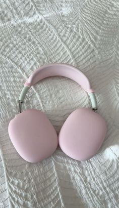 two pink headphones laying on top of a bed