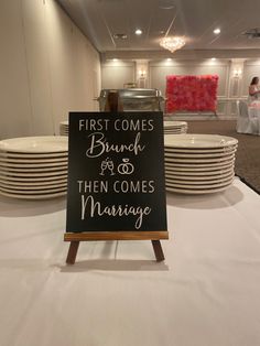 a sign that says first comes brunch and then comes marriage next to stacks of plates