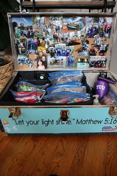 an open suitcase filled with lots of items on top of a wooden floor next to a wall