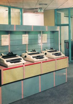 four old fashioned typewriters are lined up in a row on the counter at an office