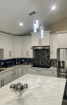 a large kitchen with white cabinets and marble counter tops, an island in the middle