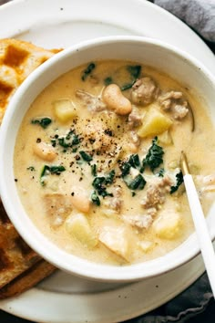 a white bowl filled with soup on top of a plate next to some pita bread