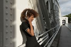 a woman with headphones leaning on a bridge