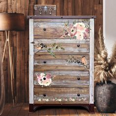 an old wooden chest with flowers painted on the front and sides, sitting next to a lamp