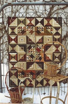 a chair and table with a quilt on it in the snow next to some baskets