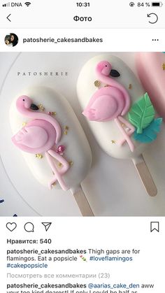 two pink flamingos on top of white cake pops with green leaves and gold flakes