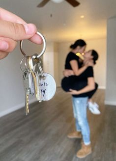 a man and woman standing in an empty room holding keys to each other with the keychain hanging from them