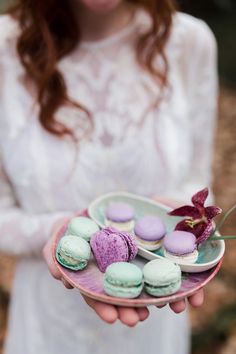 a woman holding a plate with macaroons on it