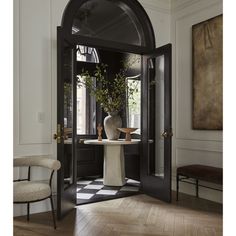 an entry way with black and white walls, wood flooring and large vases on the table