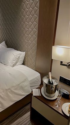 a hotel room with a bed, wine bottle and champagne on the tray in front of it