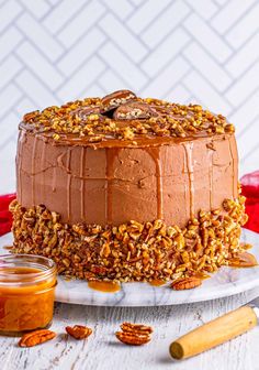 a chocolate cake with pecans and caramel on the top is sitting on a white plate