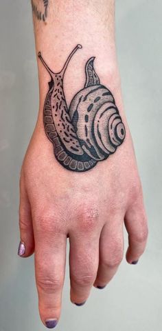 a hand with a snail tattoo on it