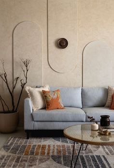 a living room with a blue couch and coffee table in front of a beige wall