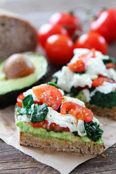 an avocado sandwich with tomatoes, spinach and feta cheese on it