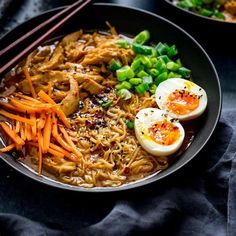 two bowls filled with ramen, carrots and hard boiled eggs