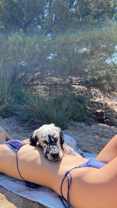 a woman laying on top of a towel next to a dog