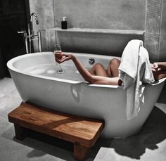 a woman laying in a bathtub holding a glass of wine